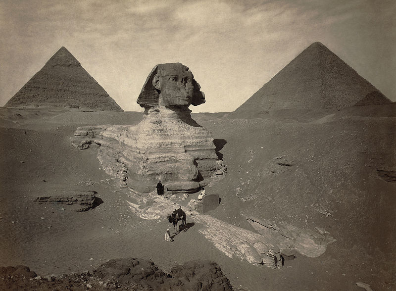 The Great Sphinx being excavated, starting in 1817 AD. Its paws are already covered in restoration stones from Roman times and a head that is obviously too small for the body, which is extremely weathered.